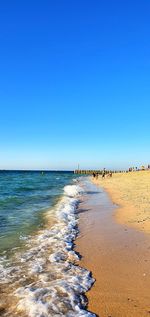 Scenic view of beach against clear blue sky