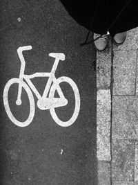 Cropped image of man standing by bicycle drawing on road