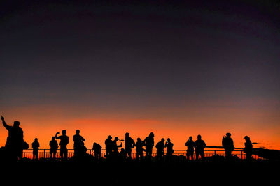 Silhouette people standing against sky during sunset