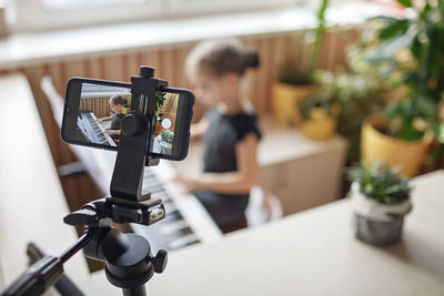 Close-up of camera recording girl playing piano