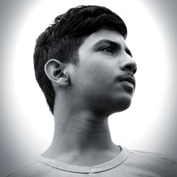 Portrait of young man looking away against white background