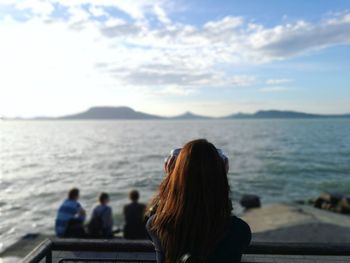 Rear view of people looking at sea against sky