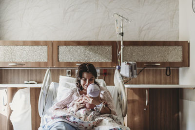 Mid view of mother in hospital bed looking at newborn son