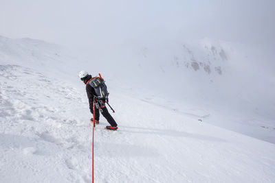 High angle view of man climbing snow covered mountain