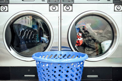 Close-up of basket against the washing machine in launderette