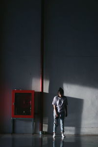 Full length of young woman standing by wall in building