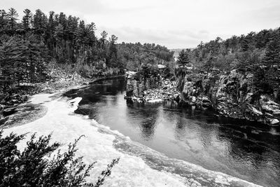 Scenic view of waterfall in forest against sky