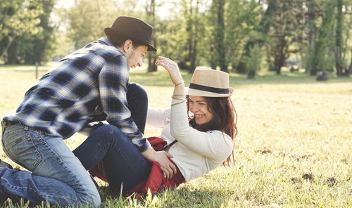 Happy couple enjoying on grass against trees at park