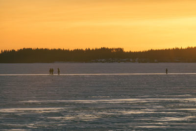 Silhouette person in lake against sky during sunset