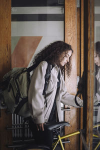 Female architect carrying backpack while leaving with bicycle from building