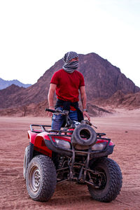 Man riding motorcycle on desert against sky