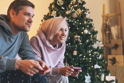 Young man sitting on christmas tree