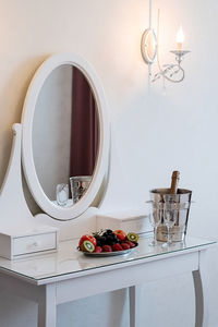 Romantic in hotel room, bottle of champagne, ice bucket, glasses and fruits.