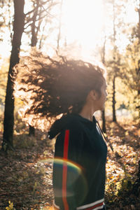 Man standing by tree trunk in forest