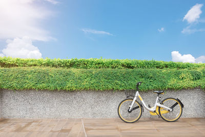 Bicycle on road amidst field against sky