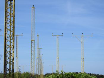Low angle view of transmission towers against blue sky