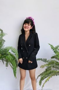 Portrait of young woman standing against plants