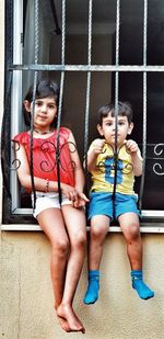 Portrait of siblings sitting in window