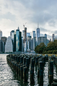 Modern buildings by river against sky in city