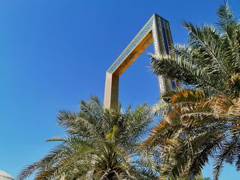 Low angle view of palm trees against clear blue sky