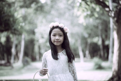 Portrait of young woman standing against trees