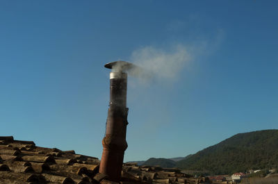 Smoke emitting from chimney against sky