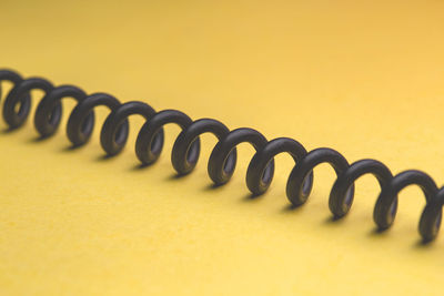 High angle view of spiral cable on yellow background