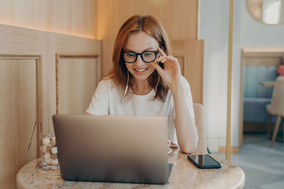 Young woman using laptop while sitting on table