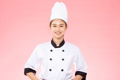 Portrait of smiling woman against pink background