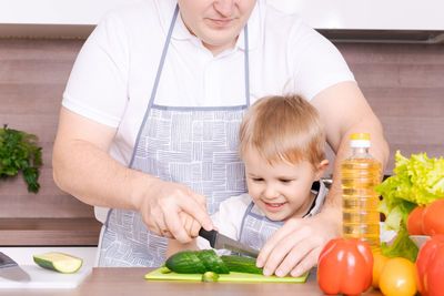 Loving father and little preschooler son cooking cut vegetables for salad