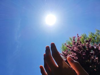 Low angle view of hand against bright sun