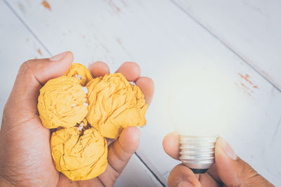 Cropped hand holding bulb and dessert above table