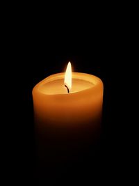 Close-up of burning candle against black background