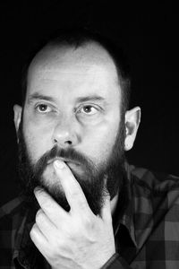 Close-up of thoughtful man against black background