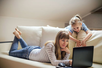 Woman using mobile phone while sitting on sofa at home