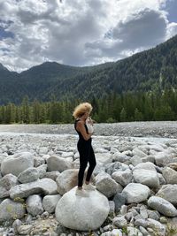 Rear view of woman standing on rock against sky