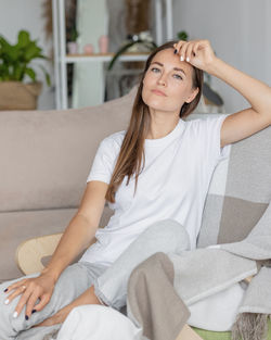 Portrait of young woman sitting on sofa at home