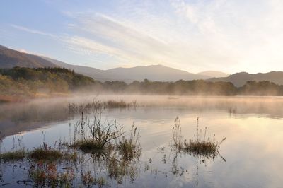 Scenic view of lake and mountains against sky during sunrise