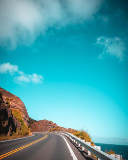 Empty road along landscape against blue sky