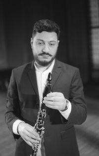 Man holding clarinet while standing at studio