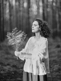 Portrait of young woman standing in forest