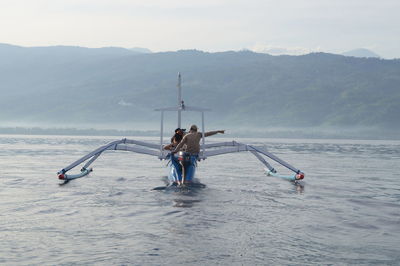 People on beach against mountain range