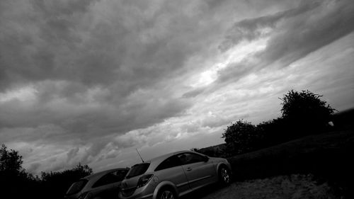 Cars on road against cloudy sky