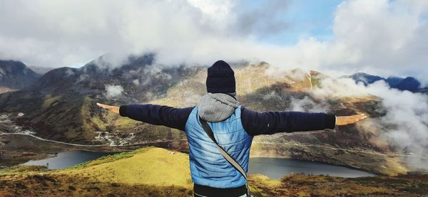 Rear view of man standing on mountain against sky