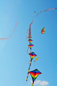 Low angle view of kites flying against sky