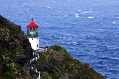 High angle view of lighthouse on cliff by sea