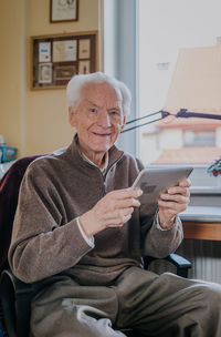 Portrait of smiling senior man using digital tablet at home