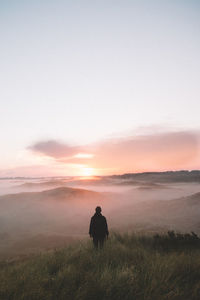 Silhouette man walking on field against sky during sunset