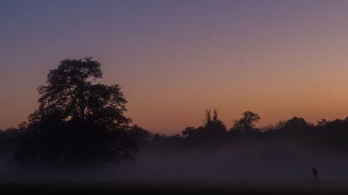 Scenic view of landscape against clear sky during sunset in foggy weather