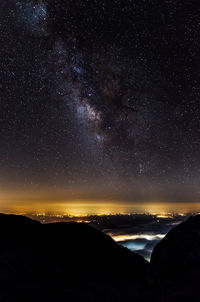 Scenic view of silhouette mountains against star field